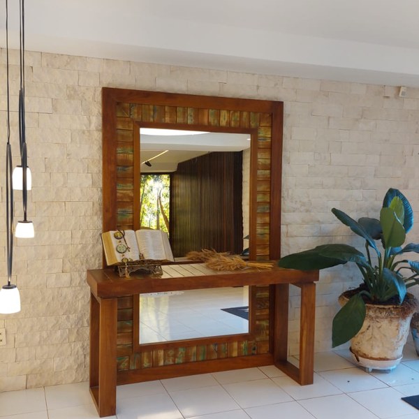 Hall com aparador, espelho de moldura de madeira e planta diante de parede em rock face limestone claro