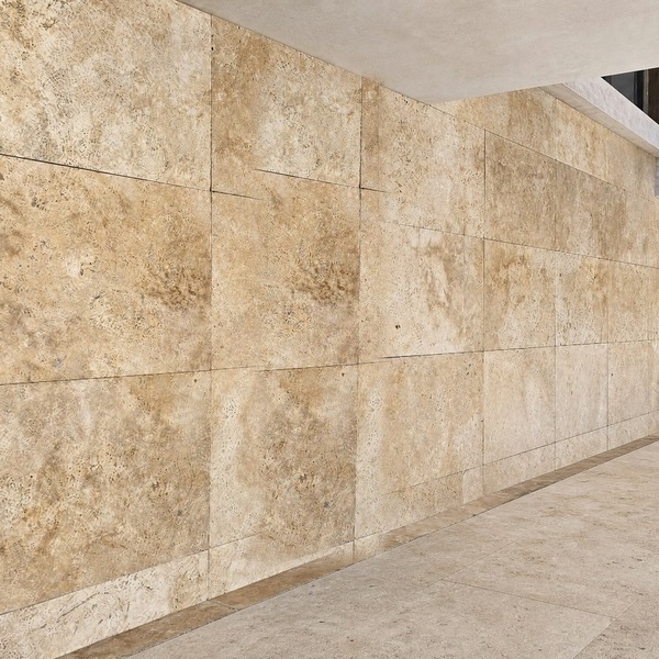 Parede externa revestida em placas grandes de travertino romano anticato