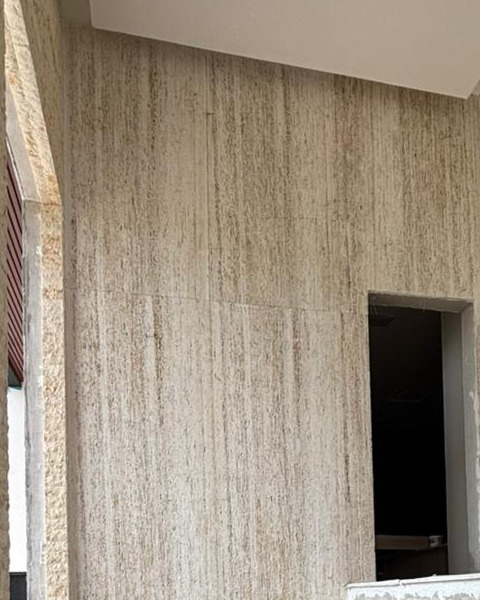 Parede externa revestida em placa serrada de travertino Vaticano, de superfície plana e junta fina